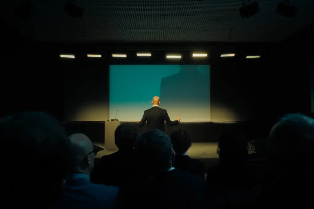 Talk on stage for the audience, in a dark hall