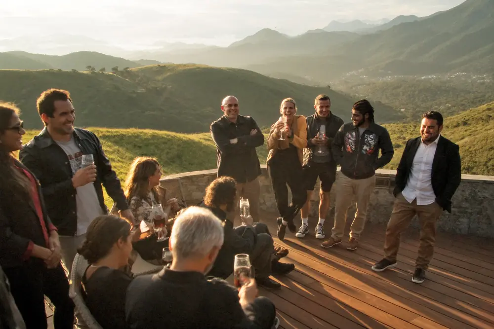 Club members laughing on a terrace in the mountains, at sunset